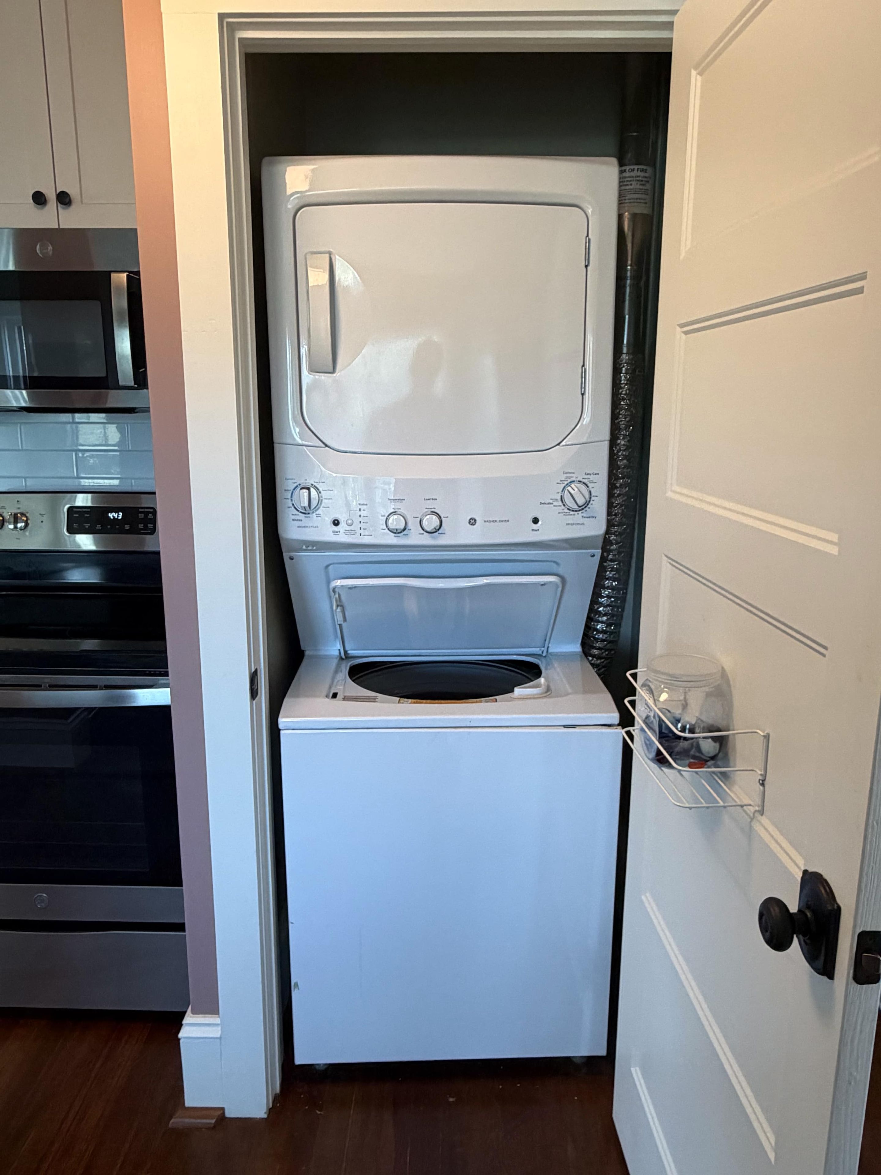 Une petite buanderie équipée d’un lave-linge et d’un sèche-linge, d’un four à micro-ondes et d’un meuble de rangement.