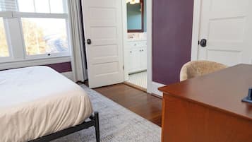 A bedroom with a bed, a desk, and a bathroom visible through an open door.