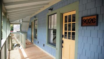 A covered porch with a wooden floor and a door marked '902C'.