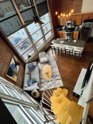 A modern kitchen with a dining area, large windows, and a staircase. - Stay Roanoke | Chic downtown 1BR with study loft (Roanoke)