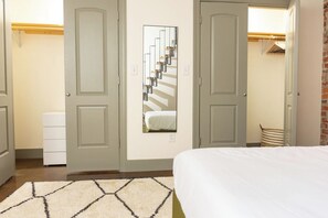 A bedroom with a bed, a dresser, a mirror, and a closet. - Stay Roanoke | Downtown Loft, Fast WiFi & Views (Roanoke)