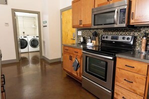 A kitchen with wooden cabinets, a stainless steel oven, a microwave, and a dishwasher. - Stay Roanoke | Downtown Loft, Fast WiFi, City View (Roanoke)
