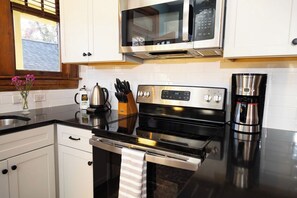 A kitchen with white cabinets, a stainless steel range, a microwave, and a coffee maker. - Stay Roanoke | 4BR Near Greenway, Dining, Drinks (Roanoke)