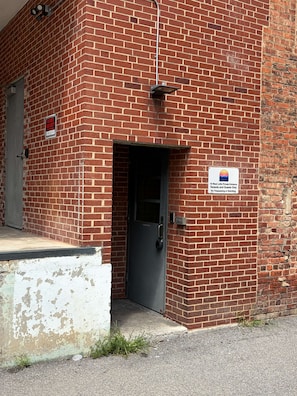 En byggnad av tegel med en dörr märkt med texten ”Westwood” och en skylt som anger: ”Endast för hyresgäster och besökare till West Lofts, ingång endast för dem. Otillåten tillträde och försäljning förbjuden”.