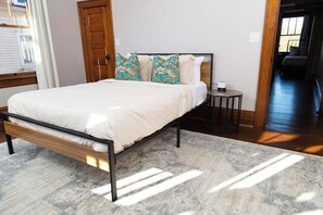 Ein Schlafzimmer mit Bett, Kissen, einem kleinen Tisch und einem Teppich.
