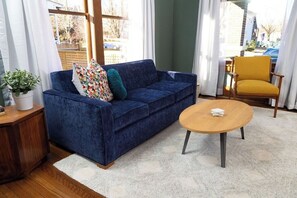 A living room with a blue sofa, a wooden coffee table, a yellow armchair, and a potted plant. - Stay Roanoke | Historic 2BR Near Dining & Trails (Roanoke)
