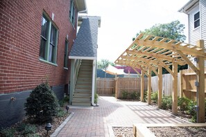 A brick house with a wooden pergola, a staircase, and a small garden area. - Stay Roanoke | Walkable 2BR Near Greenway (Roanoke)