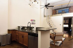 Cozinha moderna com máquina de lavar louça, geladeira e área de refeições com uma cadeira.