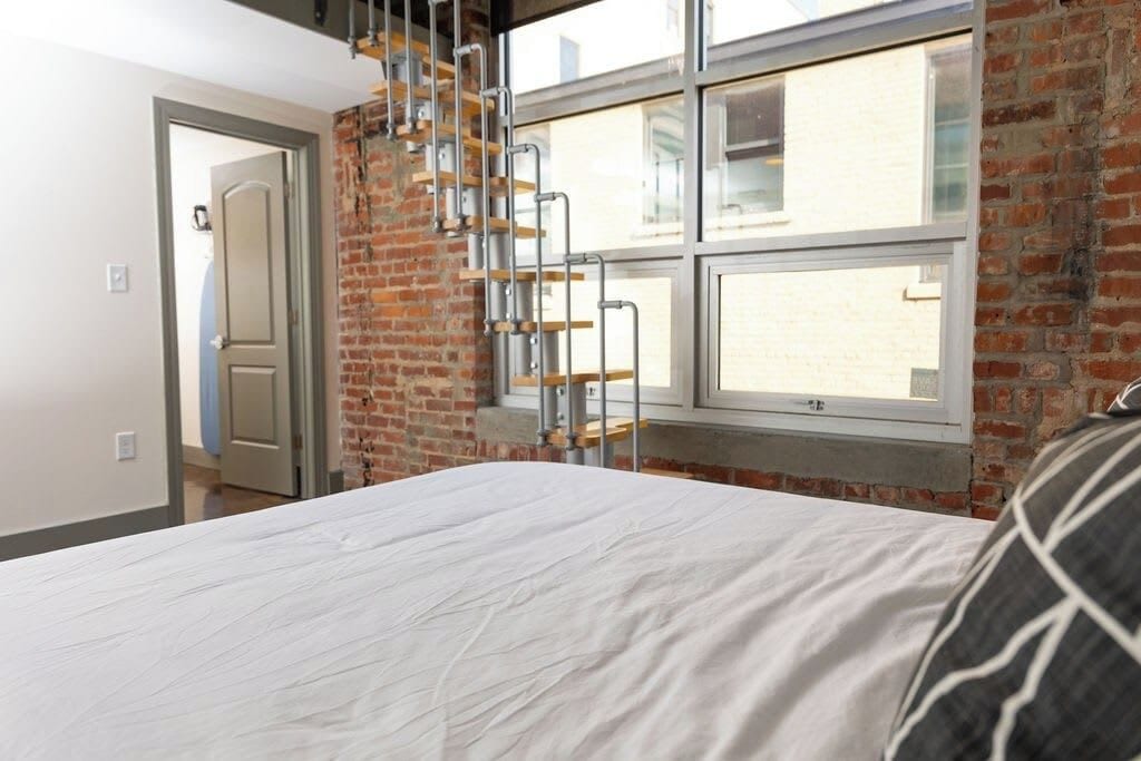 Une chambre à coucher avec un lit, un mur en briques, une fenêtre et une porte.