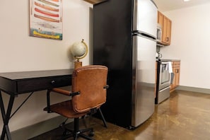 A kitchen with a black refrigerator, a wooden cabinet, and a globe on a shelf. - Stay Roanoke | Downtown 2BR w/exposed brick charm (Roanoke)