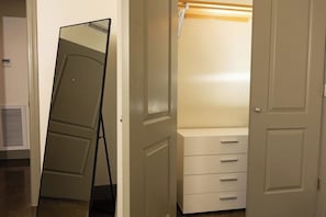 Un placard avec un miroir, une commode blanche et une étagère en bois.