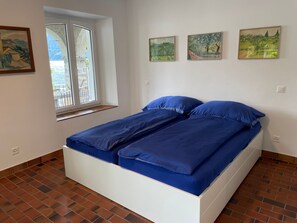 Ein Zimmer mit einem Bett, einem Fenster und drei Bildern an der Wand.