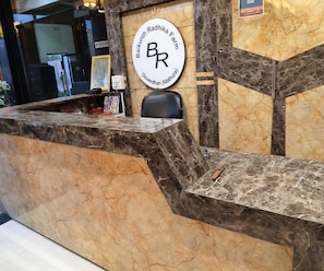 A reception desk with a marble counter, a framed picture, and a chair.