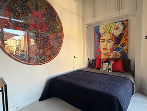 A bedroom with a large circular tapestry, a bed with a dark blue bedspread, and a colorful painting above the bed. - Frida Kahlo private 1-bedroom loft  in vibrant Houston (Houston)