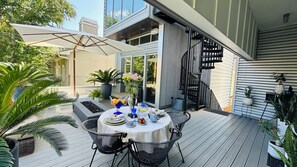 An outdoor patio with a round table set for dining, surrounded by chairs, potted plants, and a modern staircase. - Frida Kahlo private 1-bedroom loft  in vibrant Houston (Houston)
