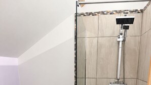 Une salle de bain comprenant des toilettes, une douche avec un pommeau de douche amovible et un lavabo blanc.
