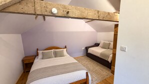 Une chambre avec un plafond en pente, des cadres de lit en bois et une petite table de chevet.