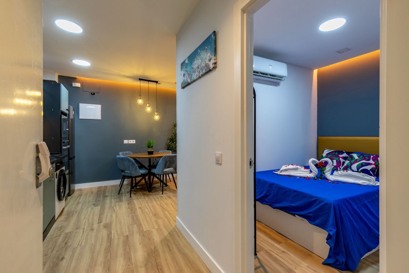 Una habitación pequeña con cama, un rincón de comedor y una kitchenette.