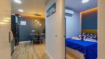Una habitación pequeña con cama, un rincón de comedor y una kitchenette.