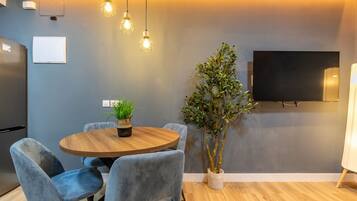 Un comedor moderno con una mesa redonda de madera, sillas tapizadas en azul y lámparas colgantes.