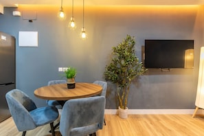 A modern dining area with a round wooden table, blue upholstered chairs, and hanging pendant lights. - Appartement 2 chambres moderne et calme - Marqués Vadillo (Madrid)