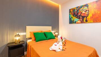 Una habitación de hotel con una cama, almohadas verdes, una mesita de noche con una lámpara y un cuadro en la pared.