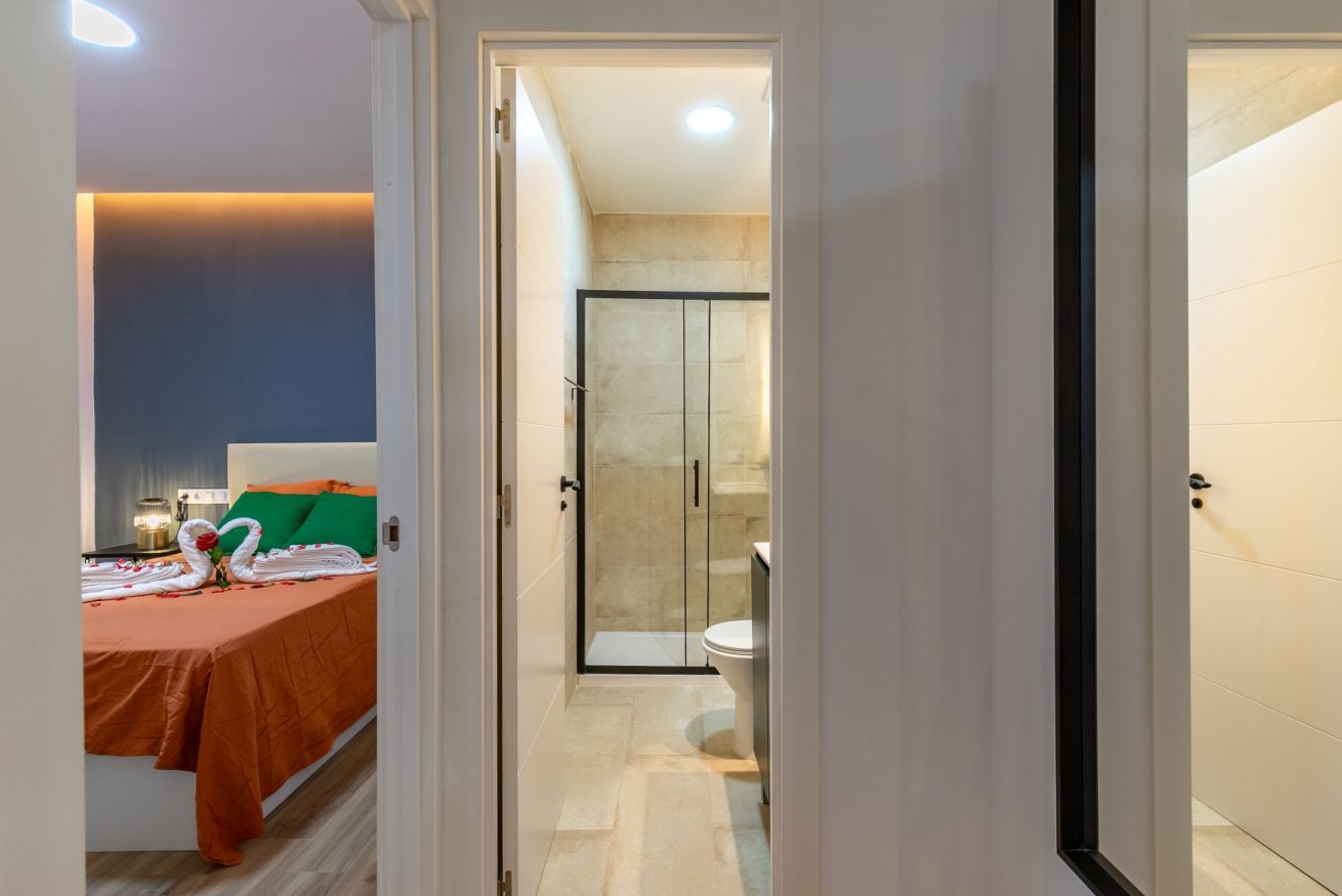 Habitación de hotel con cama, baño con cabina de ducha de vidrio y un inodoro visible.