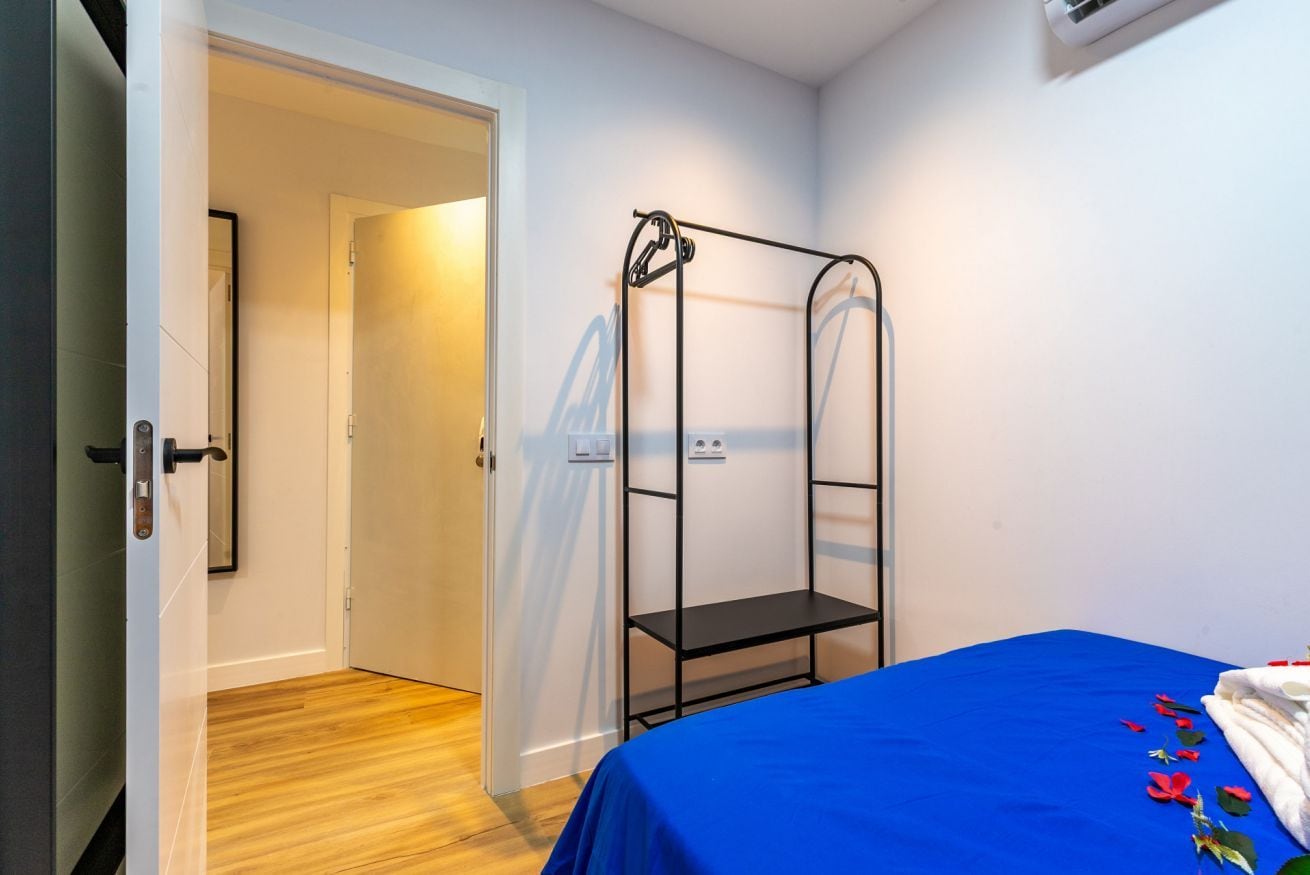 Una habitación con literas, una puerta que da a otra habitación y una mesita pequeña.