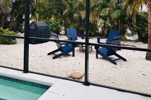 A poolside area with lounge chairs and a covered grill. - 708 N Shore in Anna Maria, FL (Anna Maria)