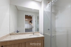 Ein modernes Badezimmer mit Duschkabine aus Glas, einem Waschbecken mit Holzschrank und einem großen Spiegel.