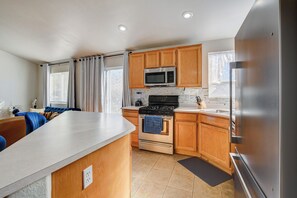 A modern kitchen with wooden cabinets, a stainless steel refrigerator, a microwave, and a stove. - Experience luxury and convenience in this stylish 3-bedroom, 2-bath home. (North Las Vegas)