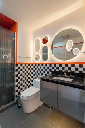 A modern bathroom with a checkered tile backsplash, a toilet, a sink with a mirror, and a glass shower enclosure.