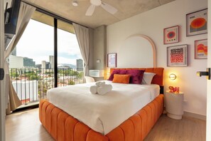 A hotel room with a large bed, a city view, and modern decor.