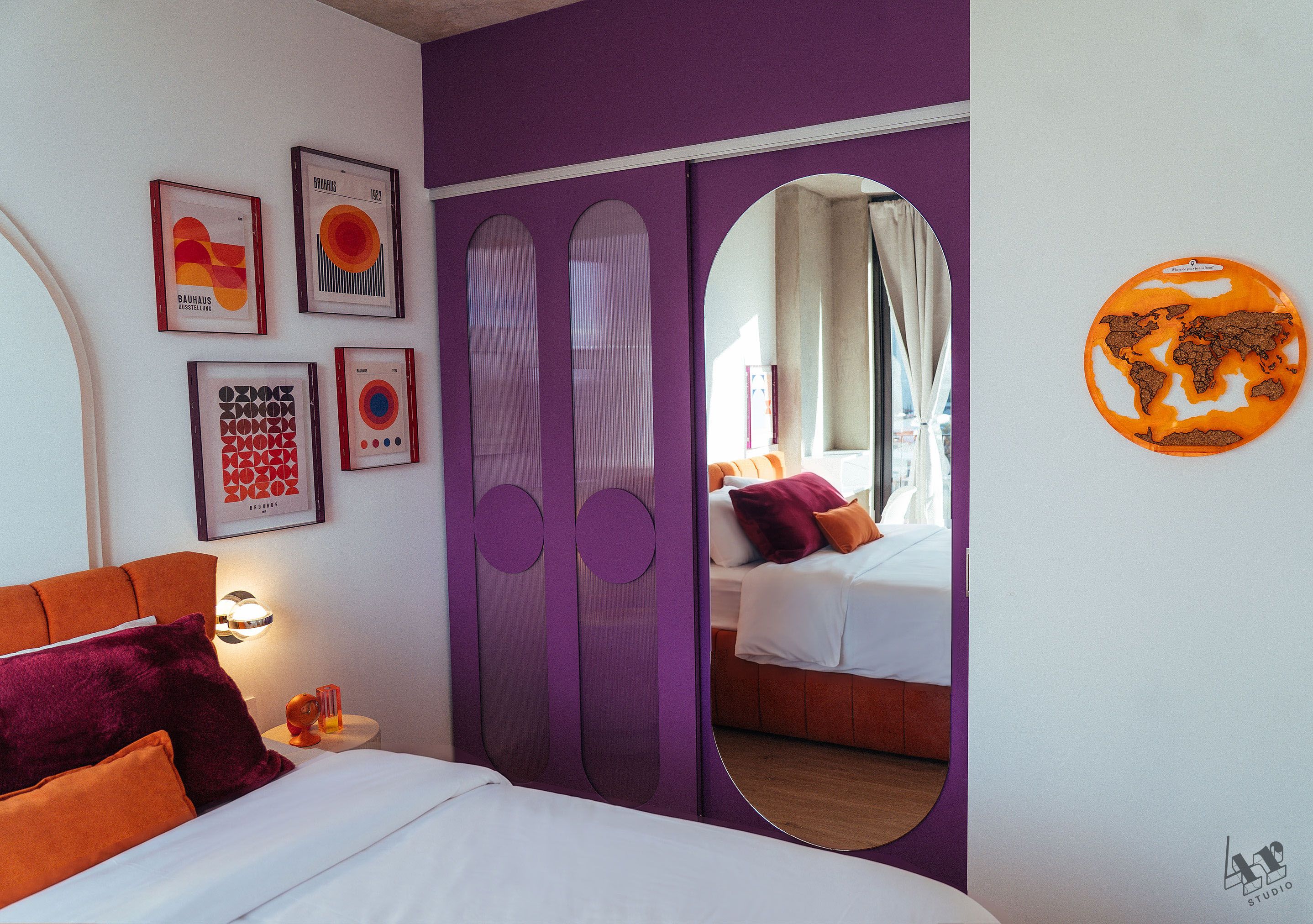 Une chambre à coucher avec un lit, un miroir et des œuvres d’art accrochées au mur.