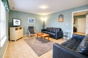 A living room with a sofa, armchair, coffee table, and a TV on a stand. - Parrot Bay Townhouse 30 | Pet Friendly (Ocean City)
