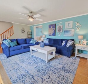 A living room with a blue sofa, white coffee table, and a patterned rug. - Davenport Creek | Dock, Kayaks & Sleeps 12 (White Stone)