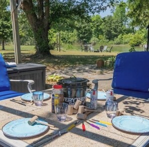 An outdoor dining area with a table set for two, featuring a pot, condiments, and utensils. - Davenport Creek | Dock, Kayaks & Sleeps 12 (White Stone)
