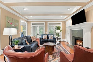 A spacious living room with a fireplace, two sofas, a coffee table, and leather chairs. - Hot Tub · Estate on the RTJ Fairway · Sleeps 16+ (Bessemer)