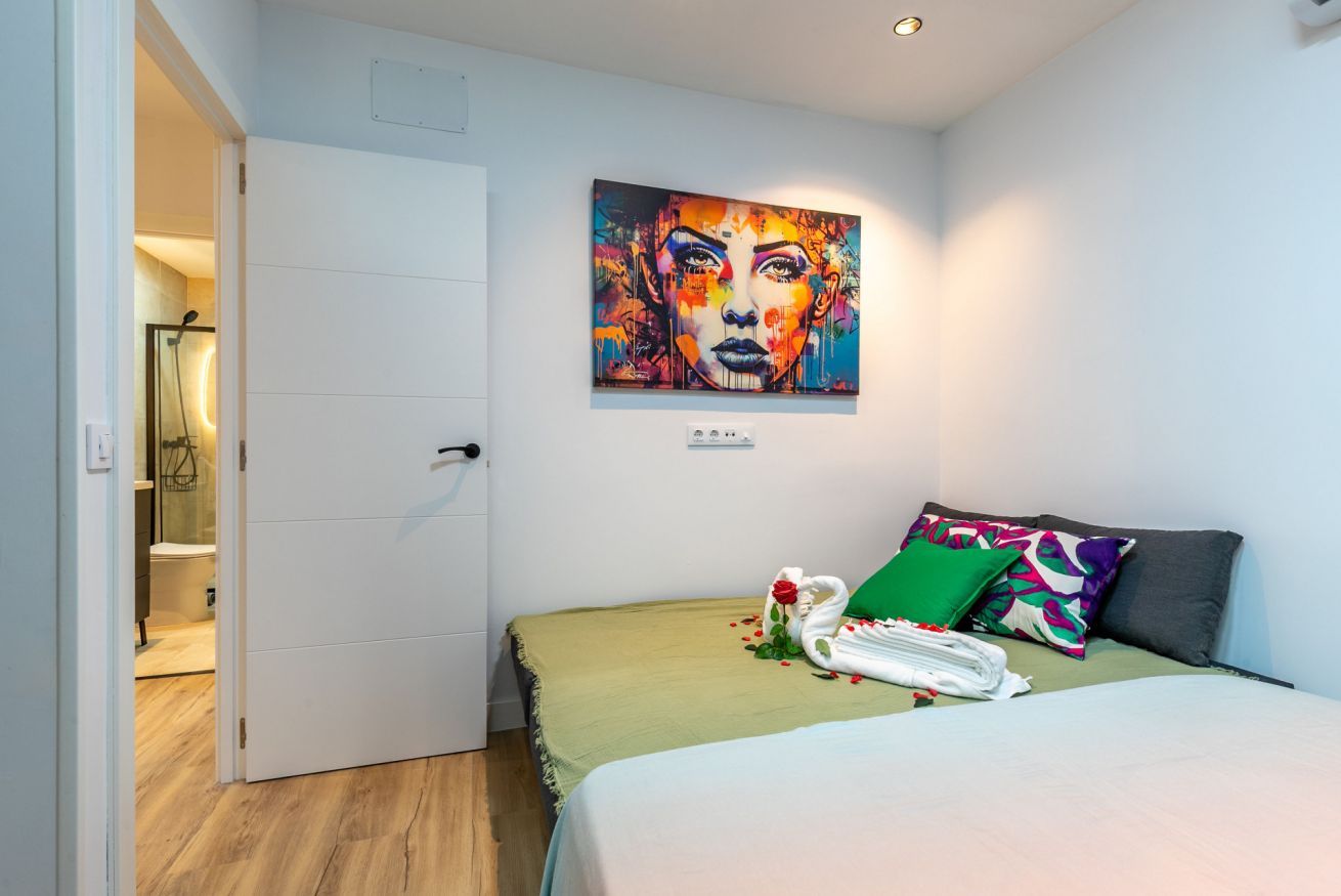 Una habitación de hotel con cama, un cuadro en la pared y una puerta que da al baño.