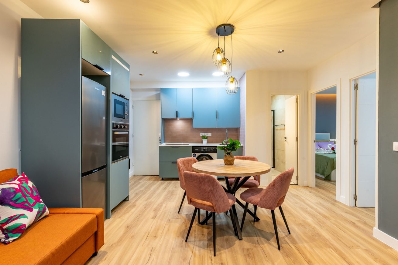 Una cocina moderna con comedor, sofá y una pequeña mesa con sillas.
