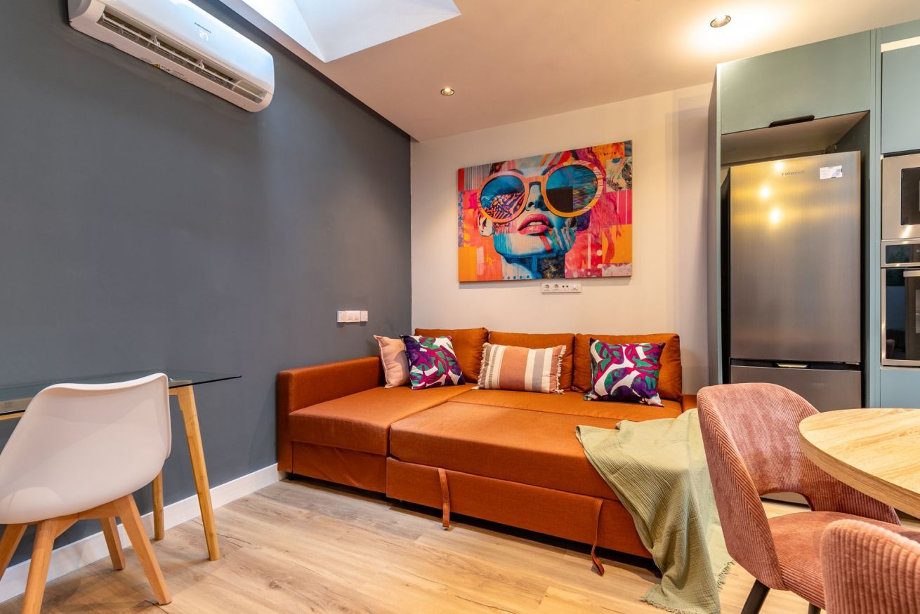 Una sala de estar moderna con un sofá, una mesa de comedor y una zona de cocina.