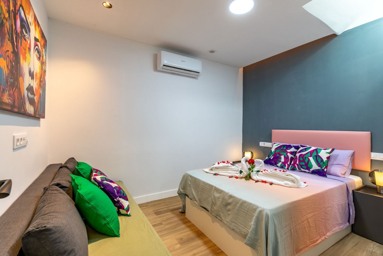 Una habitación de hotel con cama, sofá, equipo de aire acondicionado y un cuadro en la pared.