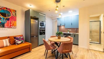 Une cuisine moderne dotée d’un îlot central, un coin repas avec une table ronde et des chaises, et une salle de douche avec des portes en verre.