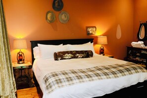 Ein Hotelzimmer mit einem Bett, zwei Nachttischlampen, einem Nachttisch, einem Spiegel und einer Wand mit drei gerahmten Bildern.