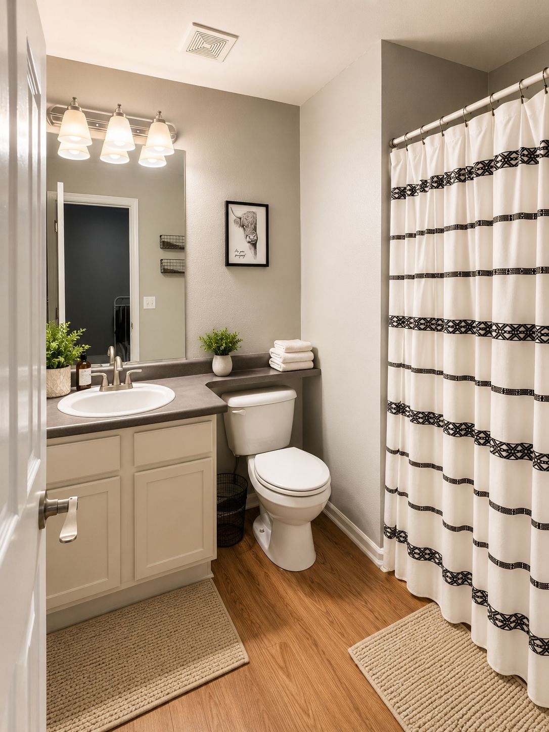 A bathroom with a sink, mirror, toilet, and shower curtain.