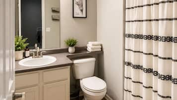 A bathroom with a sink, mirror, toilet, and shower curtain.