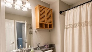 Un bagno con doppio lavandino, un water, un armadietto in legno, una tenda da doccia e uno specchio.