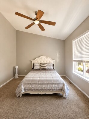 A bedroom with a bed, a ceiling fan, a window with blinds, and a standing heater. - Peaceful 3-bedroom townhome in charming Palmer Lake, perfect for families! (Palmer Lake)