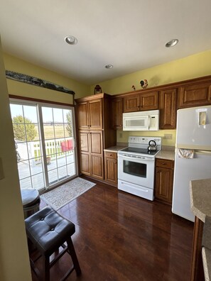 A kitchen with wooden cabinets, a white refrigerator, a microwave, and an oven.