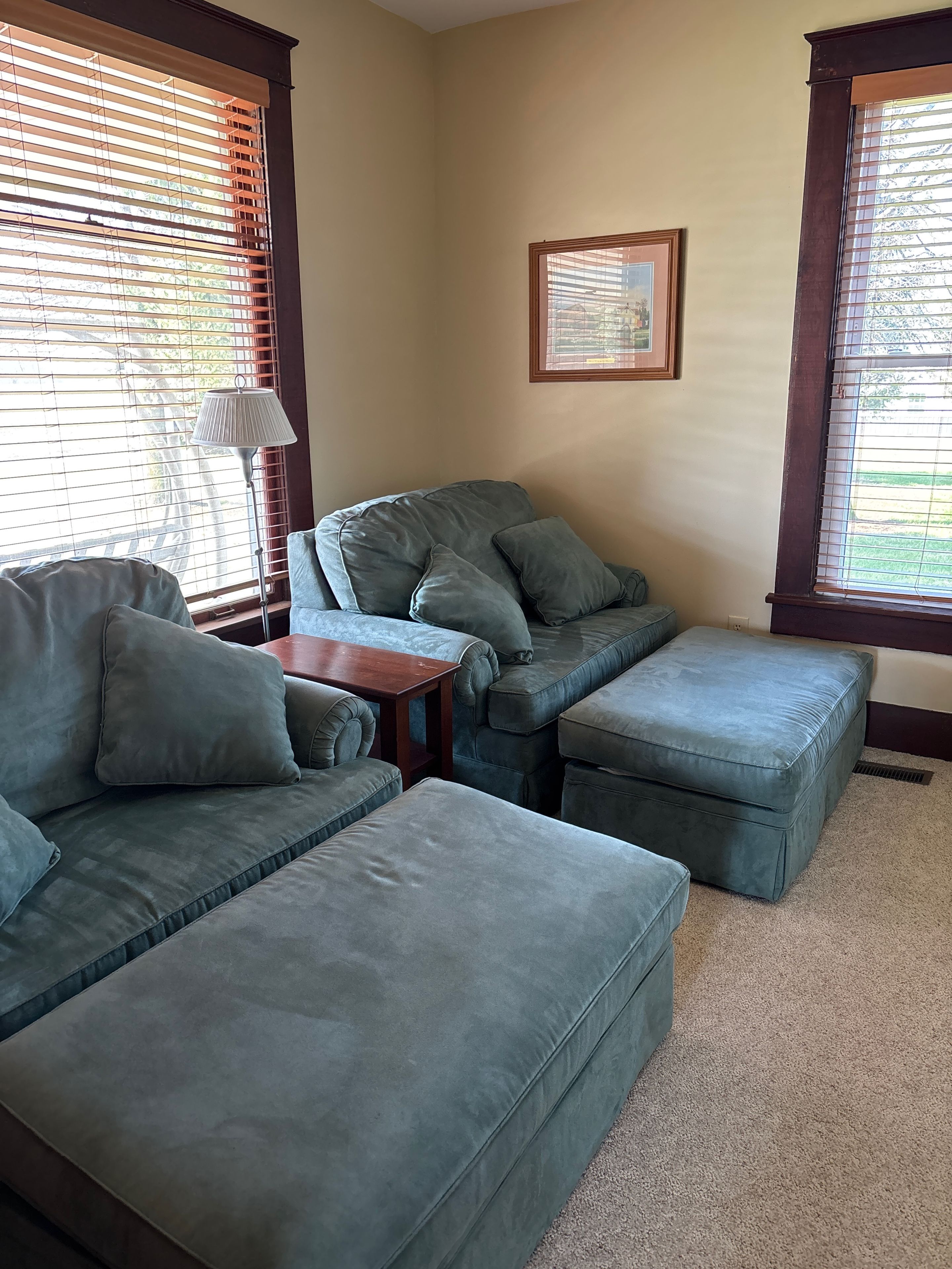 A living room with a sectional sofa, ottoman, and a small wooden table.